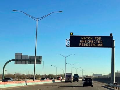 An electronic sign flashes "Watch for unexpected pedestrians," Dec. 20, 2022, on the highway next to the fenced US-Mexican border just east of downtown El Paso, Texas, next to one of the three bridges that connect the Texas city with the sprawling metropolis of Juarez, Mexico.