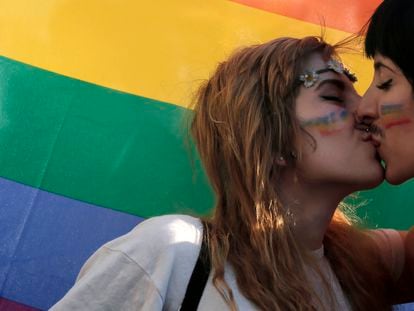 Two women kiss in front of a rainbow flag, the symbol of the gay rights movement, during the Gay Pride parade in central Athens, Saturday, June 14, 2014.