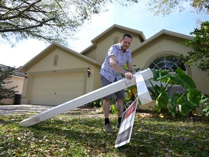 Scott Collett removes the real estate sign from the front of his home he recently purchased, on February 21, 2023, in Valrico, Florida.