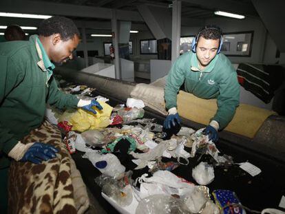 Two workers manually separate garbage at the Valdemíngomez waste plant.