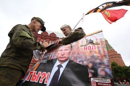 Two men hold an image of Vladimir Putin on Red Square in Moscow, Saturday. 
