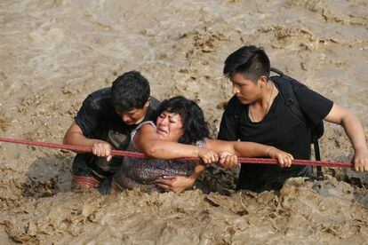 A woman is helped across a flooded street in Huachipa, Peru on March 17. Floods in the country have left 75 dead, 263 injured, 20 missing and 630,000 affected in total.