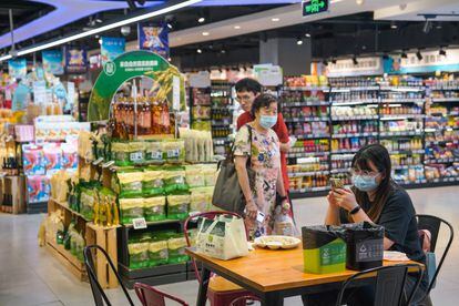 A woman wearing a face mask uses her cellphone at a mall in Beijing, China, 31 July, 2023.