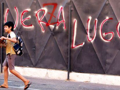 A boy passes in front of anti-Lugo graffiti with the words altered to read &quot;Power to Lugo.&quot;