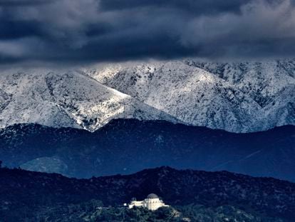 Storm clouds and snow are seen over the San Gabriel mountain range behind Griffith Observatory in the Hollywood Hills part of Los Angeles on Sunday, Feb. 26, 2023.