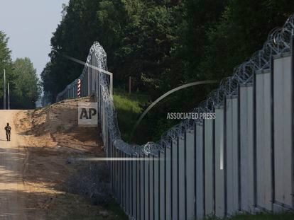 A Polish border guard patrols the area of a built metal wall on the border between Poland and Belarus, near Kuznice, Poland, on June 30, 2022.