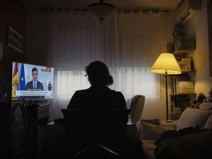 A woman watches Spanish Prime Minister Pedro Sánchez announce an extension to the state of alarm on March 28 and the freezing of all non-essential activity.