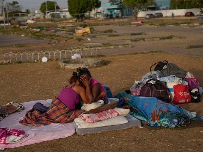 A Venezuelan migrant cries with her daughter after sleeping outdoors in the parking lot of a bus terminal in Boa Vista, Roraima state, Brazil, on April 7, 2023.