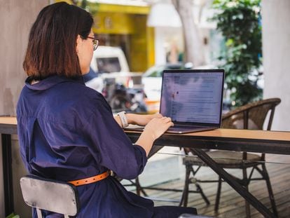 A woman uses a laptop at a café.