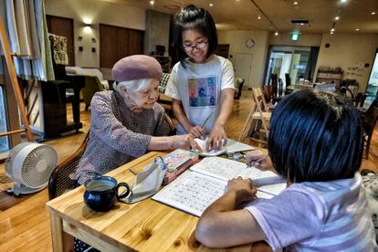 At 92, former teacher Kaneko helps two young girls with their homework. 