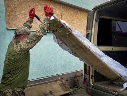 Ukrainian soldier loads the bodies of killed Ukrainian servicemen