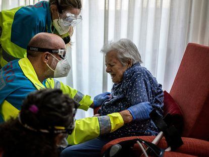 Health workers help an elderly patient in Madrid.