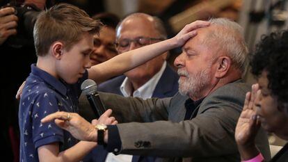 Lula da Silva receives a prayer from David Mikami, 9, during the presentation of a 'Letter to the Evangelicals', during a campaign event in São Paulo, on October 19, 2002.