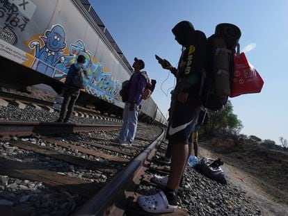 Migrants watch a train go past as they wait along the train tracks hoping to board a freight train heading north, one that stops long enough so they can hop on, in Huehuetoca, Mexico, May 12, 2023.