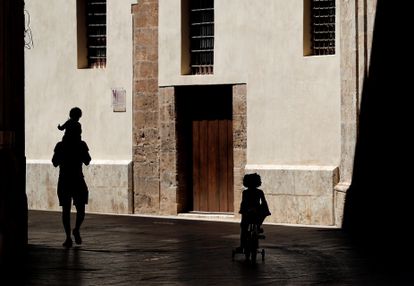 A man walks outside with his two children in Valencia.