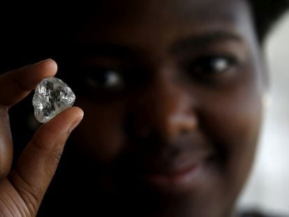 A visitor holds a precious stone during a visit to the headquarters of the De Beers diamond company in Gaborone, Botswana.