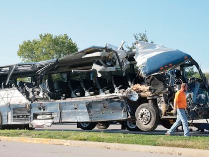 A worker helps clear the wreckage of a Greyhound bus that collided with tractor-trailers on the exit ramp to a rest area on westbound Interstate 70 in Highland, Ill., on Wednesday, July 12, 2023.