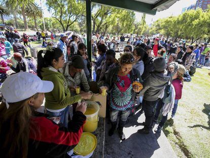 Cuban citizens on their way to the United States stranded in Quito stand in line for food and drink.