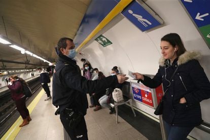 A police officer hands a mask to a commuter in Madrid‘s Metro station.
