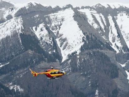 A French Civil Protection helicopter flies over the crash site area.