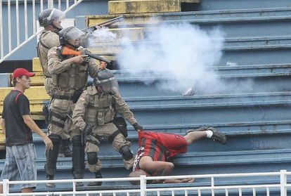 Police fire tear gas at warring supporters as another is dragged away during the Atlético Paranaense-Vasco de Gama match.