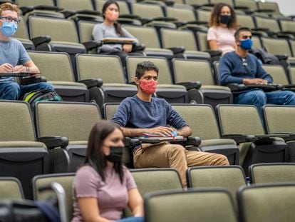 College students sitting in a lecture hall keeping social distance during the Covid-19 pandemic and wearing masks to protect from the transfer of germs.