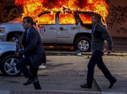 Forensic police officers walk past a vehicle ablaze in Caracas on Wednesday. 