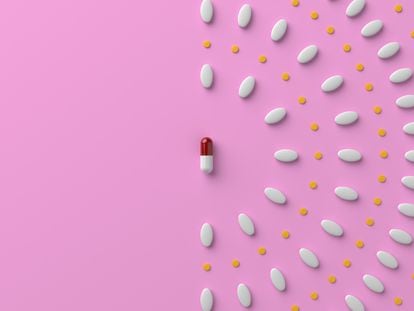 Pills and a capsule on pastel pink colored background.