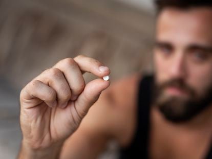 A man holds an ecstasy or MDMA pill.