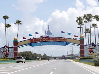 Cars drive under a sign greeting visitors near the entrance to Walt Disney World, July 2, 2020, in Lake Buena Vista, Fla.