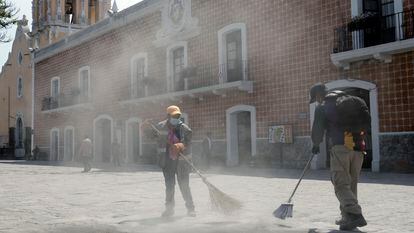 Cleaning employees sweep volcanic ash from a plaza in the city of Atlixco, in the state of Puebla.