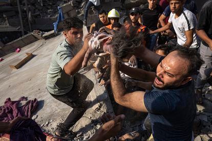 Palestinians pull the body of a young girl out of rubble from a residential building leveled in an Israeli airstrike on Al Shati Refugee Camp Thursday, October 12, 2023. 