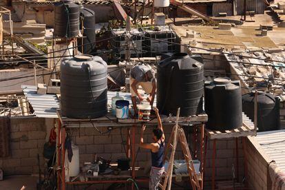Two men fill the water tanks of a house in Rafah, south of the Strip.