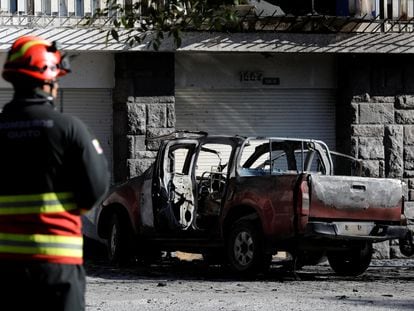 A firefighter stands near the remains of a car that exploded in Quito, Ecuador, on August 31, 2023.
