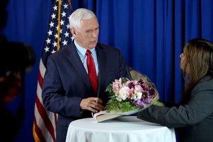 Former Vice President Mike Pence, left, is presented with flowers by Dhara Patel, of Keene, N.H., right, while signing copies of his book "So Help Me God," before the start of a GOP fundraising dinner, Thursday, March 16, 2023, in Keene, N.H.