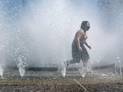 A child plays in a fountain to cool off in downtown Portland, Ore., Friday, May 12, 2023.