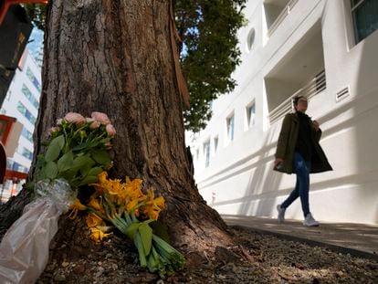 A woman walks past flowers left outside an apartment building where a technology executive was fatally stabbed in San Francisco