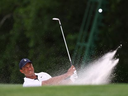 Tiger Woods plays out from a bunker on the 18th hole during the first round of the Augusta National.