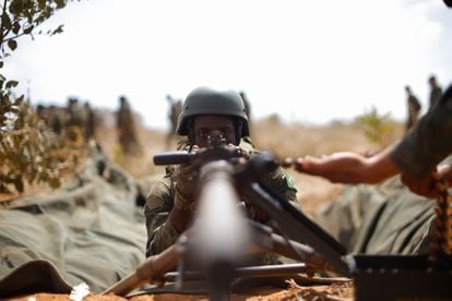 A Brazilian soldier aims a machine gun.