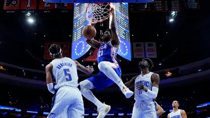 Joel Embiid of the Sixers dunks against Paolo Banchero of the Magic.