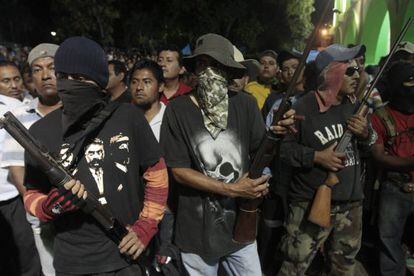 Hooded men stand guard while suspects are turned over to police in Ayutla de los Libres.
