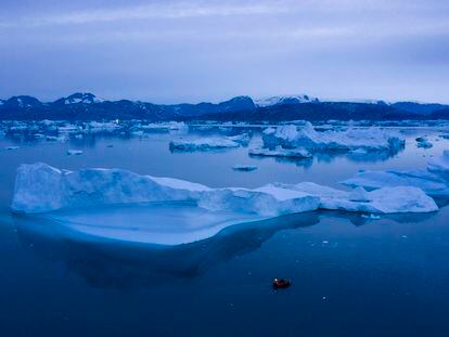 A boat navigates at night next to large icebergs near the town of Kulusuk, in eastern Greenland on Aug. 15, 2019