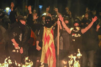 A group of people raise their arms in front of a fire during a protest in Barcelona. More than 50 fires were registered in the downtown area, according to city officials.
