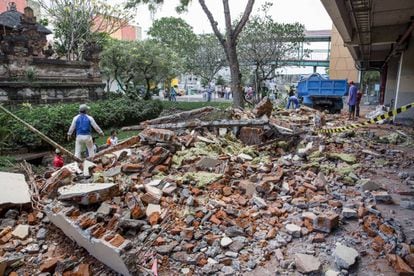 Workers cleanup parts of a shopping mall building which collapsed after an earthquake, in Denpasar, Bali.