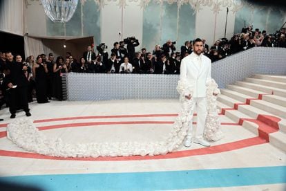 Bad Bunny attends the Gala wearing a white suit and a cape full of roses by Simon Porte Jacquemus.