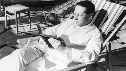 Photo of German novelist and playwright Lion Feuchtwanger seated, reading a book, 1951.