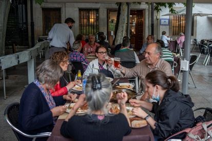 A group of people dining at a sidewalk café in Ourense.