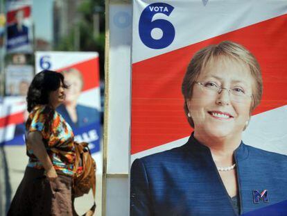 A woman walks past a campaign poster for Michelle Bachelet in Santiago.