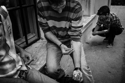 Drug addicts inject heroin on the streets of Athens.