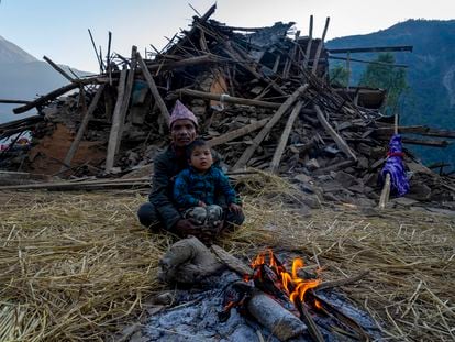 A man and a child sit in front of an earthquake damaged house in Jajarkot district, northwestern Nepal, Sunday, Nov. 5, 2023.